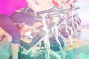 Spin class working out in a row against abstract background